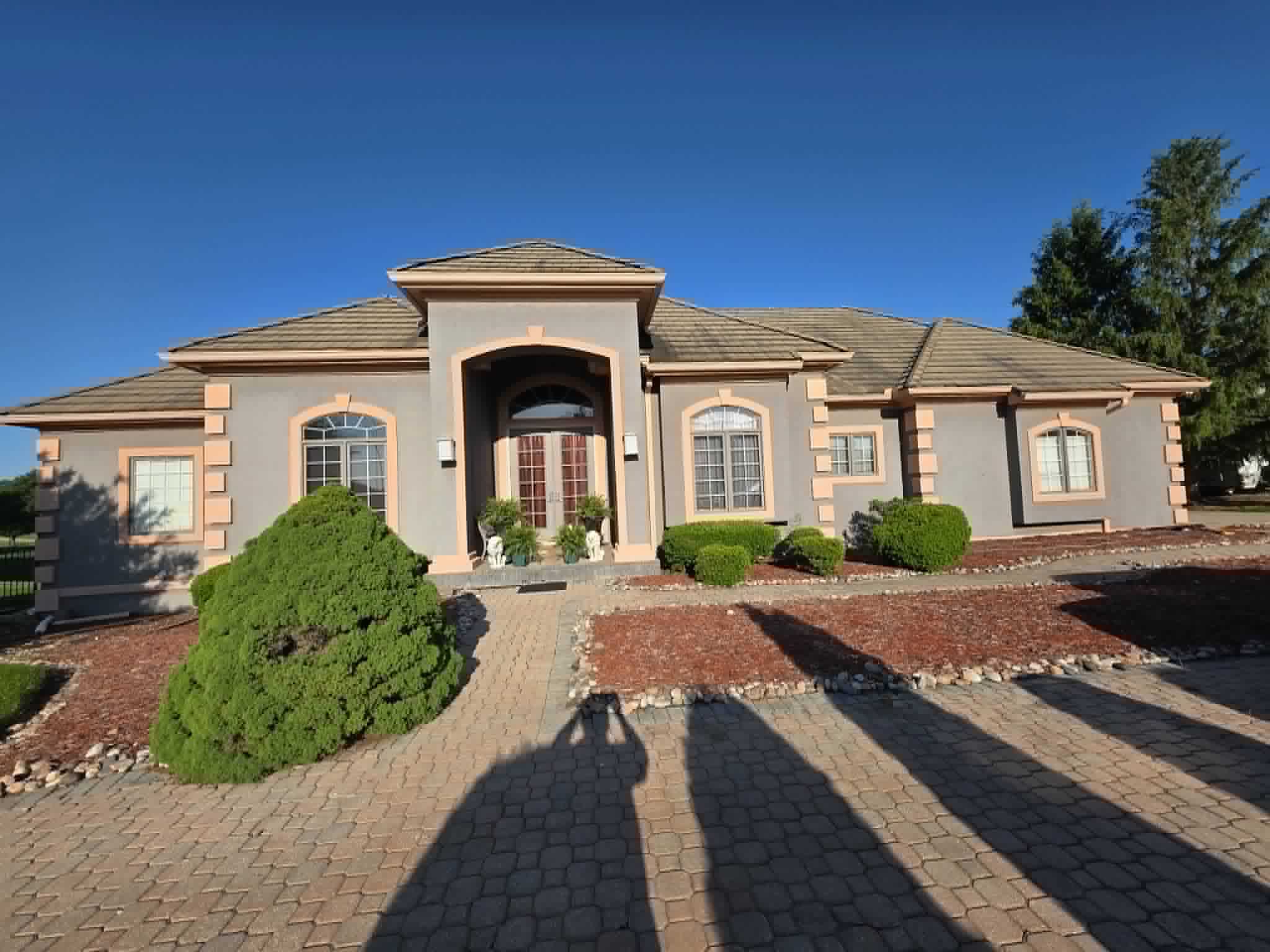 Stucco estate with faded gray and peach paint before repainting