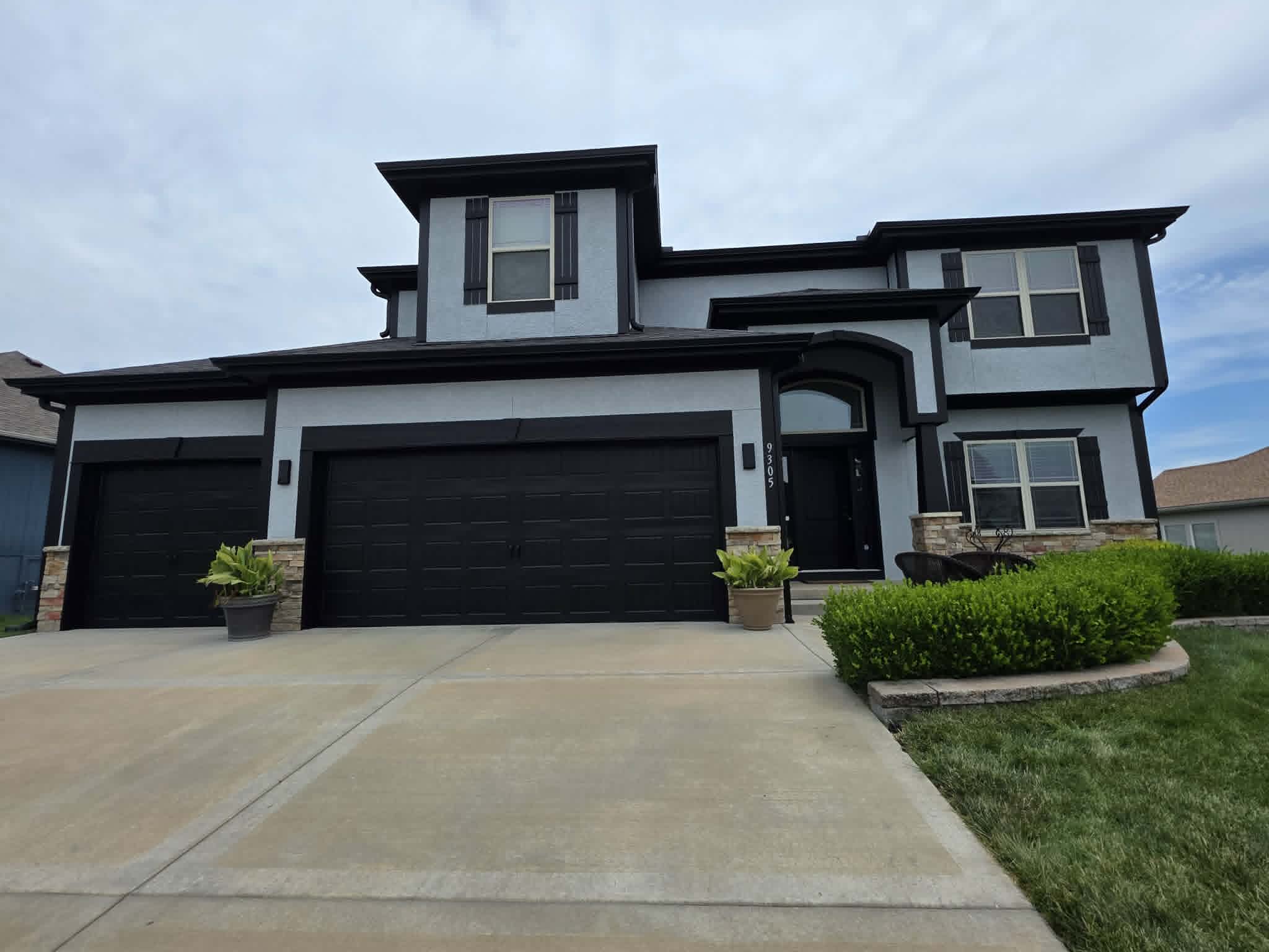 The same two-story home in light gray with a bold black trim package